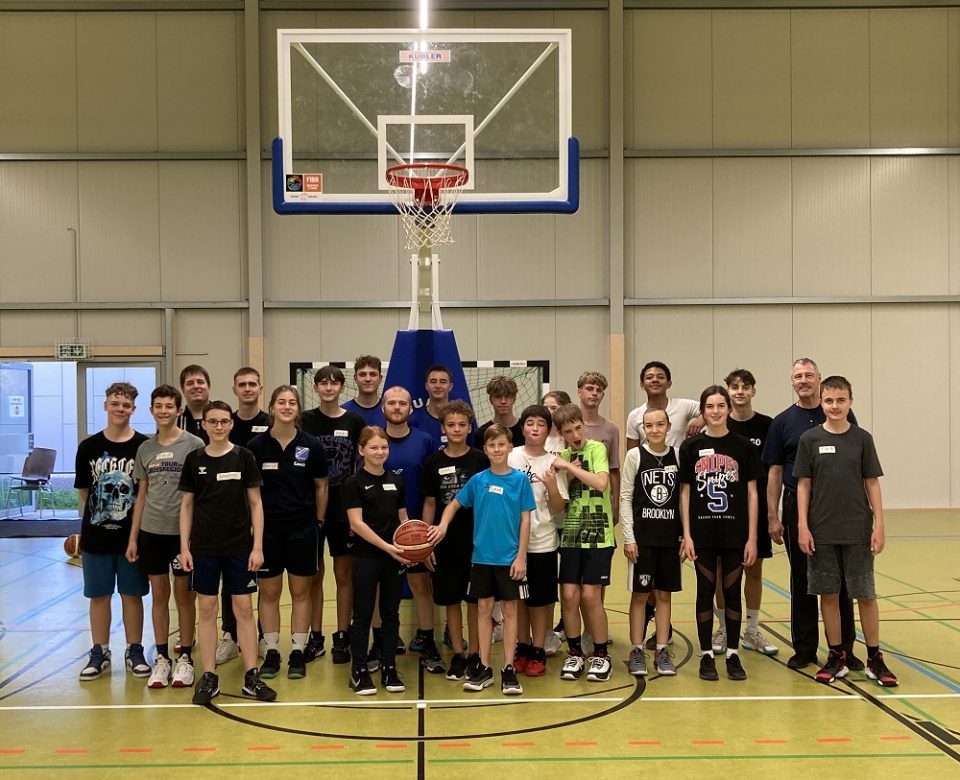 Teilnehmerinnen und Teilnehmer des Basketball Jugendcamps des TuS Mosella Schweich beim Gruppenfoto unter dem Basketballkorb in der Sporthalle