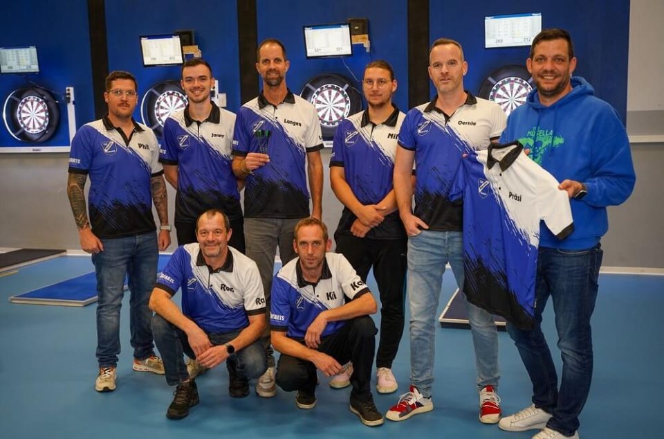Dartspieler des TuS Mosella Schweich bei einer gemeinsamen Trikotübergabe vor den Dartscheiben Dartspieler des TuS Mosella Schweich bei einer gemeinsamen Trikotübergabe vor den Dartscheiben