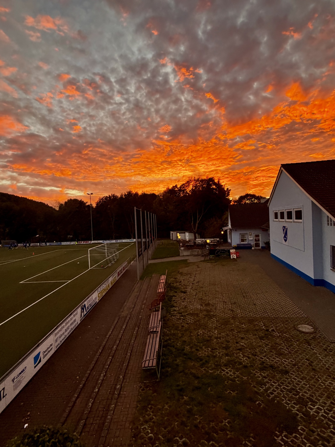 Sportplatz am Winzerkeller und Mosella Vereinsheim unter einem orangefarbenen Abendhimmel